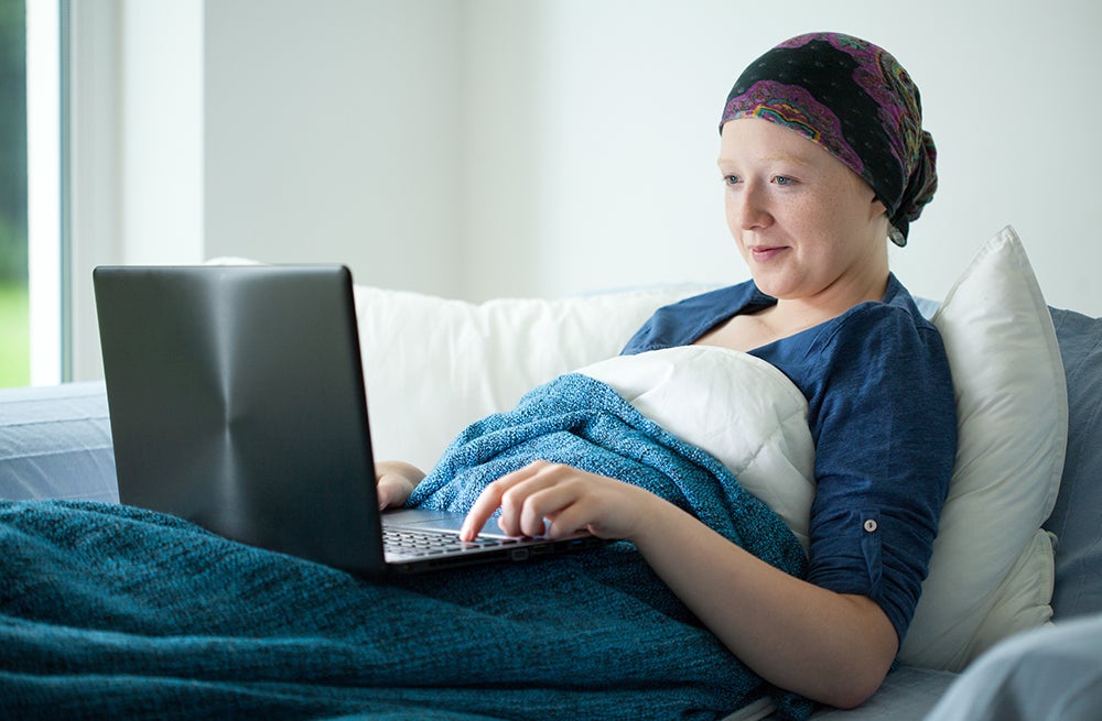 Cancer patient on couch using laptop